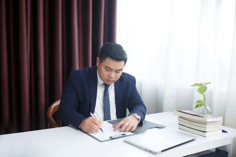 身著西裝男子在辦公桌前書寫文件